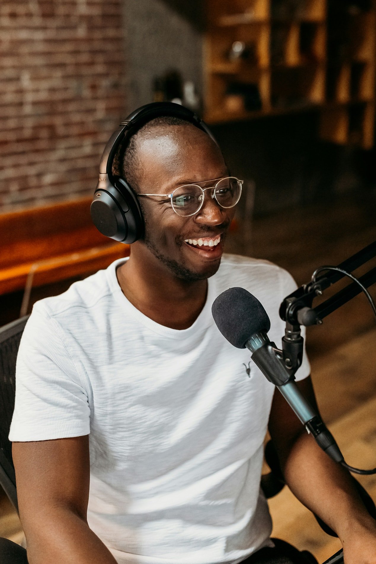 Person in a recording studio wearing headphones, smiling toward a boom microphone