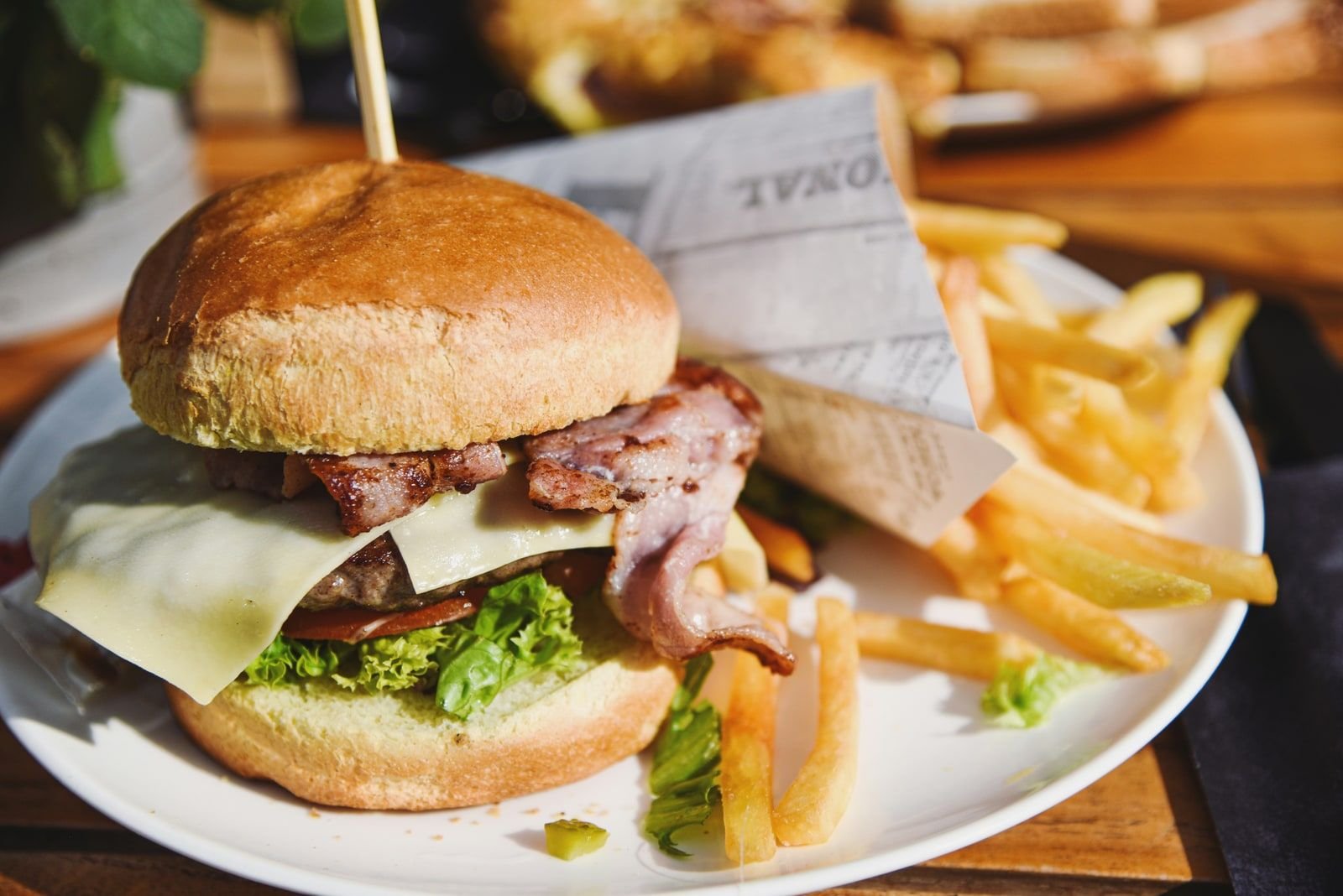Cheeseburger with bacon and fries on a plate at a casual restaurant