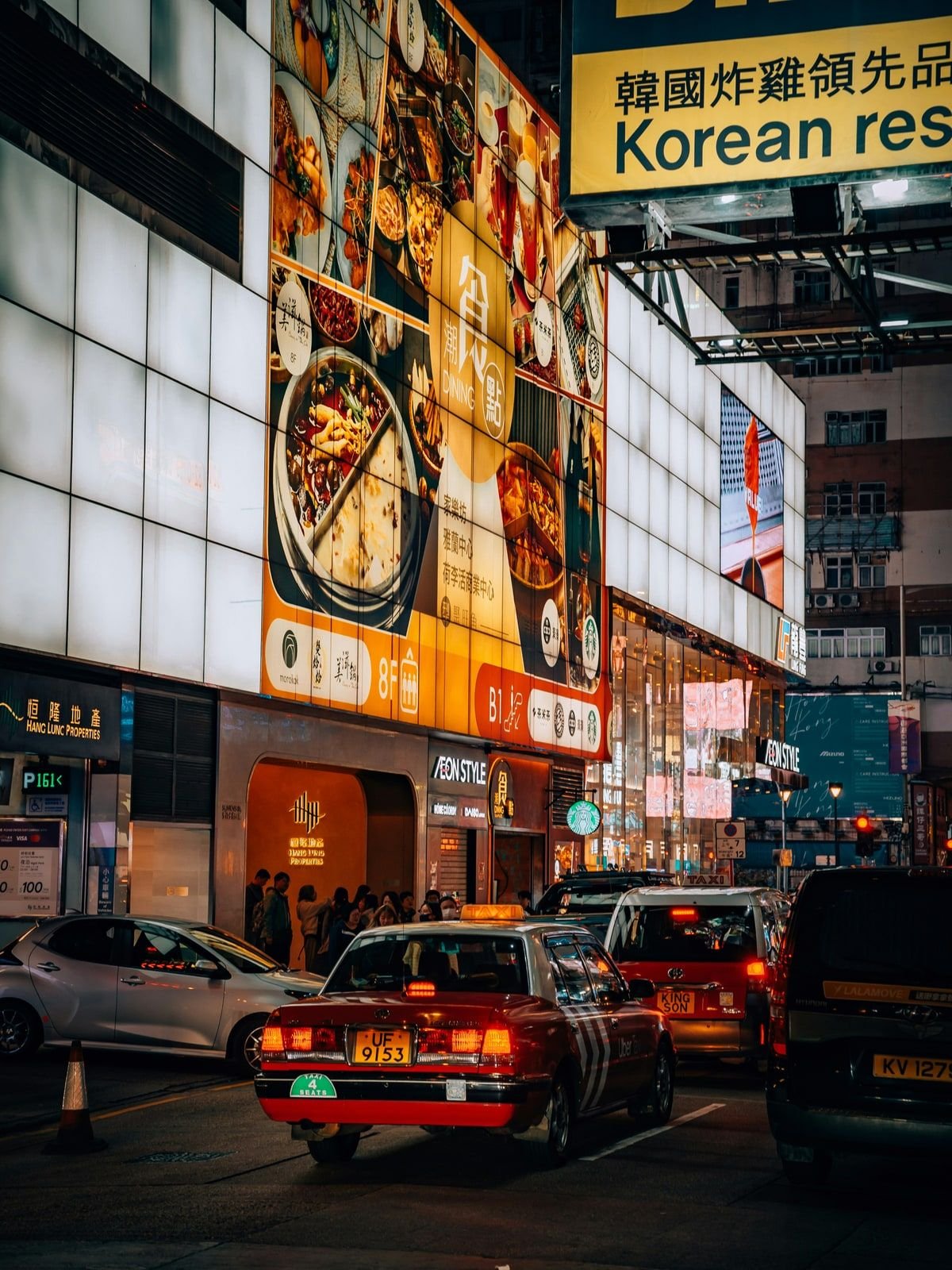 Hong Kong street at night with a large restaurant billboard and traffic below