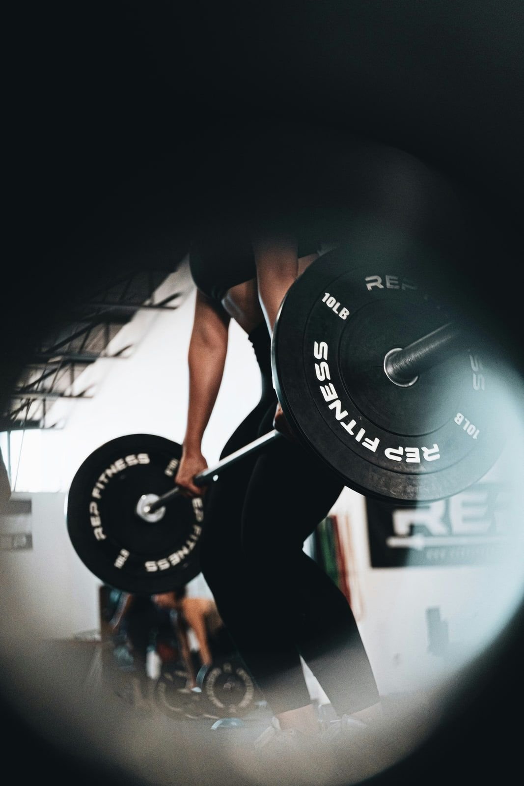 Weightlifter gripping a loaded barbell in a gym